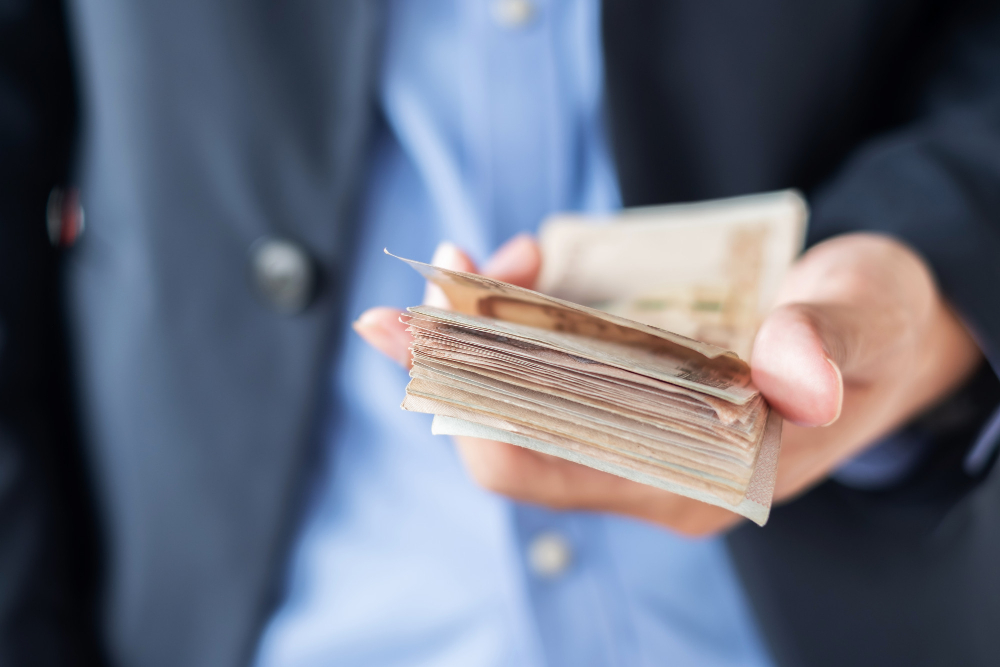 businessman hand holding thai baht banknote stack